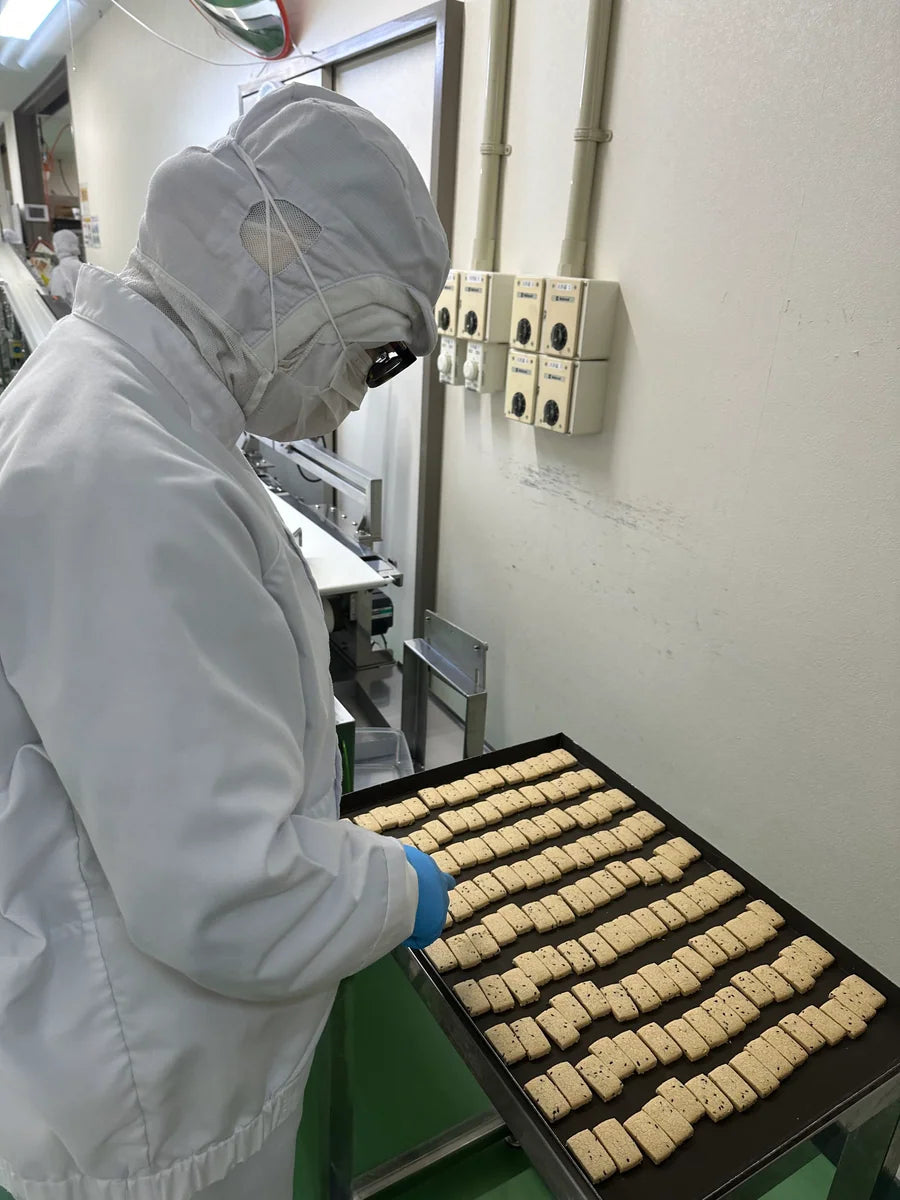 A NOGI team member inspecting rice snacks on a tray before packaging